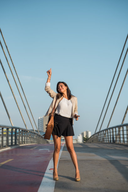 女子在街上高兴地跳舞，举手示意。垂直的图像。本空间图片下载