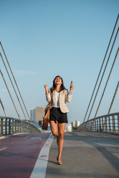 一名律师在街上拿着手机庆祝胜诉。垂直的图像。本空间图片下载
