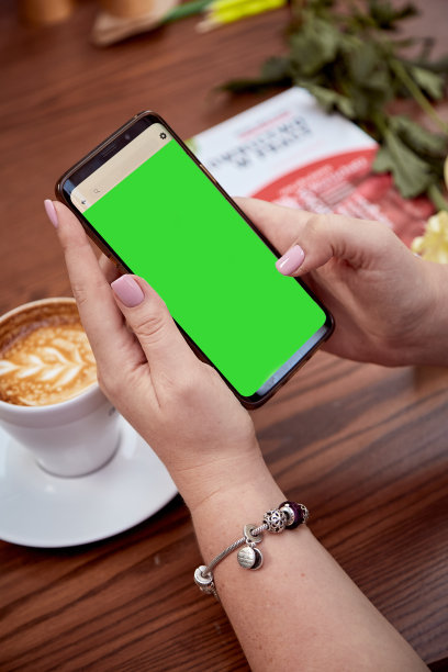 女人手中的手机屏幕和桌上的咖啡。前视图。教育，工作，自由职业者的概念图片下载