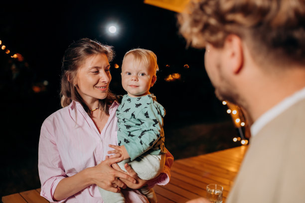幸福的家庭和可爱的宝宝一起放松，在夏天的晚上一起在舒适的篝火旁露营。户外休闲休闲的豪华露营帐篷。生活方式的概念图片下载