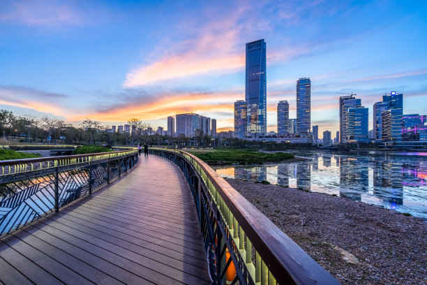 黄昏时分，城市天际线前的木制小路图片下载