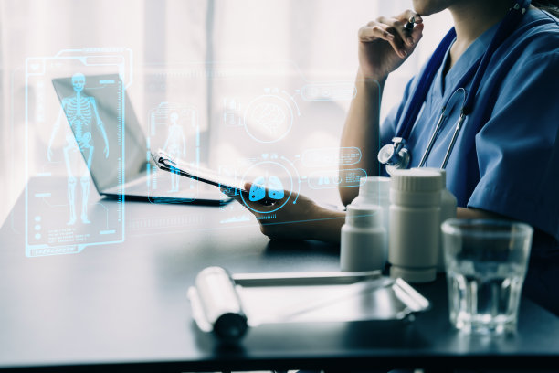 医生在笔记本电脑和平板电脑上工作，听诊器在写字板上，电子病历系统EMRs概念。图片下载