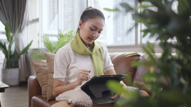 亚洲女性在家用平板电脑工作。图片下载