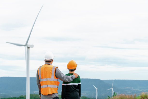 进步工程师和他儿子在山顶的风力发电场。图片下载