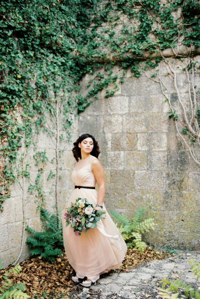 新娘站在一个长满常春藤的古老堡垒院子的角落里图片下载