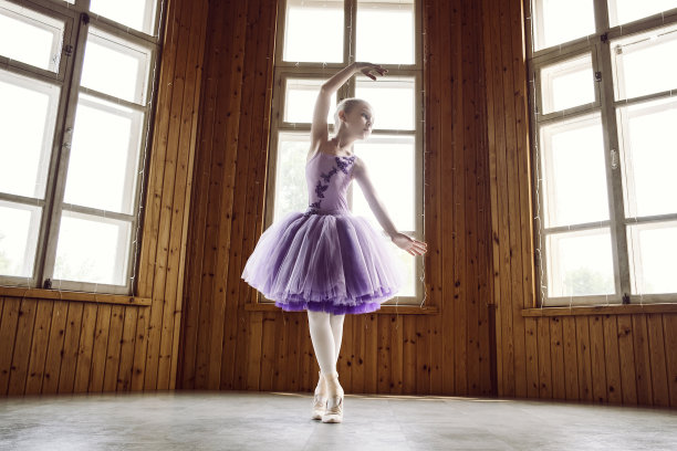 身着淡紫色连衣裙的芭蕾舞女演员在房间里展示芭蕾舞姿势图片下载