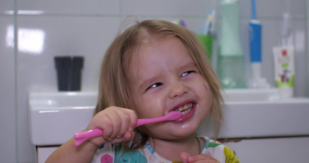 这孩子在刷牙的时候很沉迷于咬牙刷。一个小女孩在睡觉前在浴室里尽情地用牙刷刷牙。图片下载