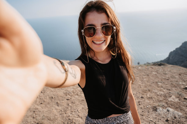 自拍是一名年轻女子以岩石和山区为背景拍摄的照片。女孩对着镜头微笑。旅游、休闲的概念图片下载