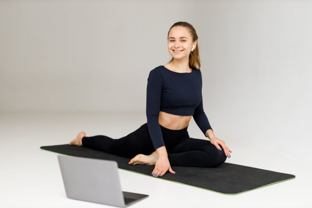 年轻积极的女子在白色背景上指导在线瑜伽课程。图片下载