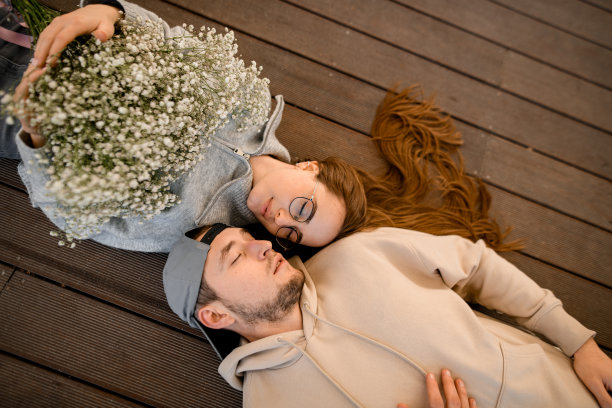 一对夫妇闭着眼睛躺在木露台上的伟大俯视图。图片下载