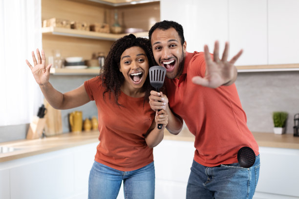 快乐的年轻非裔美国男人和女人穿着同样的T恤，对着虚拟麦克风唱歌图片下载