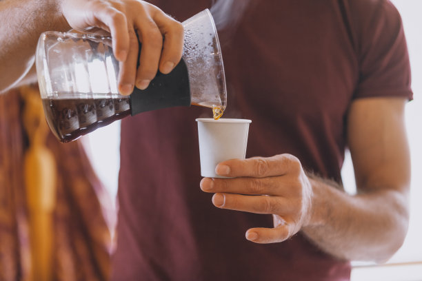 咖啡师在咖啡店里把煮好的咖啡倒进纸杯里图片下载