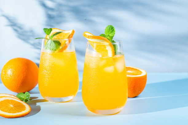 新鲜的橙汁加冰在杯子里，蓝色背景。橙色的鸡尾酒图片下载