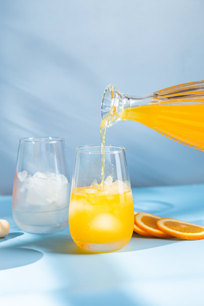 新鲜的橙汁加冰在杯子里，蓝色背景。橙色的鸡尾酒图片下载