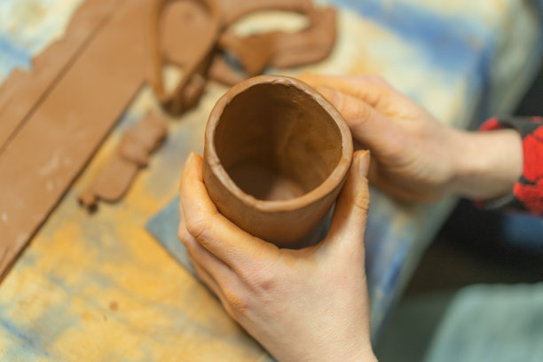 特写的人的手做一个粘土杯。陶艺教学班。波特用粘土和陶瓷制作盘子。图片下载