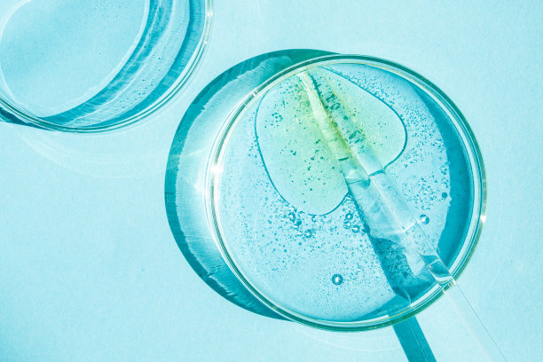 培养皿中。装有液体的皮氏杯。化学元素、油脂、化妆品。凝胶，水，分子，病毒。特写镜头。在蓝色的背景上。图片下载