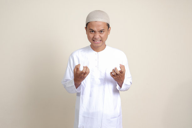 有吸引力的亚洲穆斯林男子在白衬衫的肖像愤怒的手势与手指。孤立的图像在灰色背景图片下载