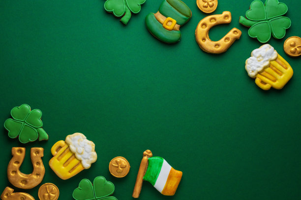 绿色背景的圣帕特里克节旗帜。硬币，马蹄铁，四叶草作为节日的象征。发短信的地方。姜饼曲奇。图片下载