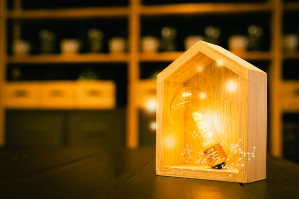桌上有木房子的灯泡，象征建筑，创意灯泡理念，电力能源或商业理念，概念生态，贷款，抵押，财产或家。图片下载