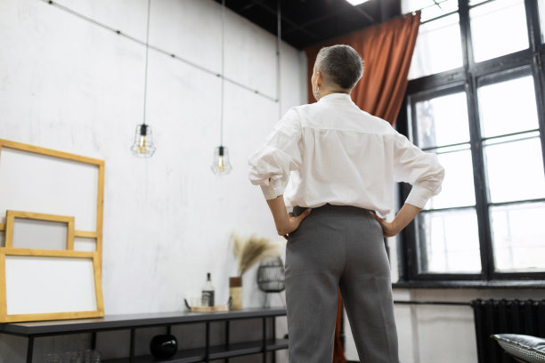 一个留着短发的时髦女人站在房间里，看着空荡荡的墙，想着要修理图片下载