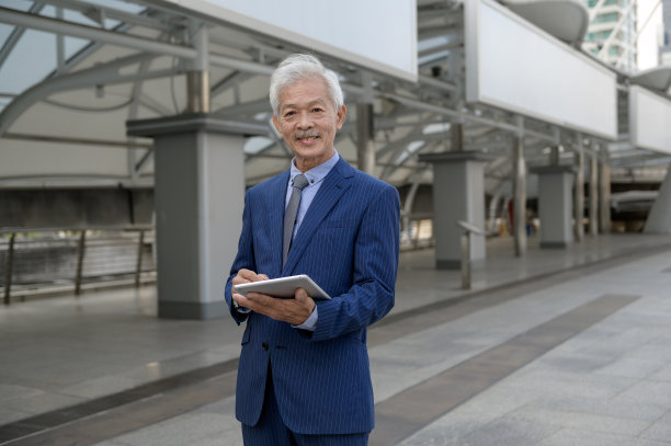 亚洲高级、成熟、中年商人在现代都市使用平板电脑图片下载