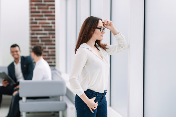 成功的女商人透过办公室的窗户往外看。图片下载