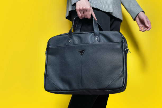 一个商业妇女的特写与一个时尚的商务包孤立在黄色背景。装笔记本电脑的包。图片下载