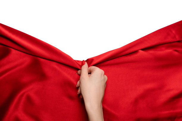 一个长着红指甲的女人的手正试图扯下一块红色的丝绸。图片下载