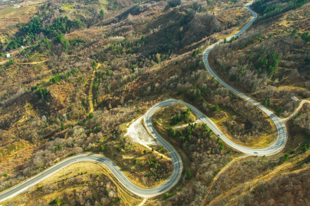 蜿蜒的山路在树木繁茂的地区。生态方法图片下载