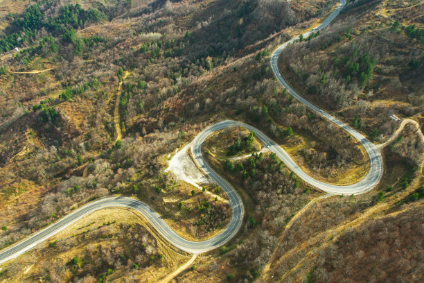 蜿蜒的山路在树木繁茂的地区。生态方法图片下载