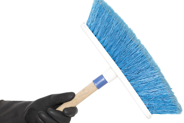 白色背景上，一只戴着黑色橡胶手套的手拿着扫帚。清洁工的手。图片下载