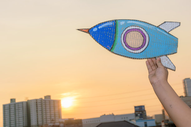 站在摩天大楼上，背光下的艺术，在模糊的城市背景上牵手发射宇宙飞船。图片下载