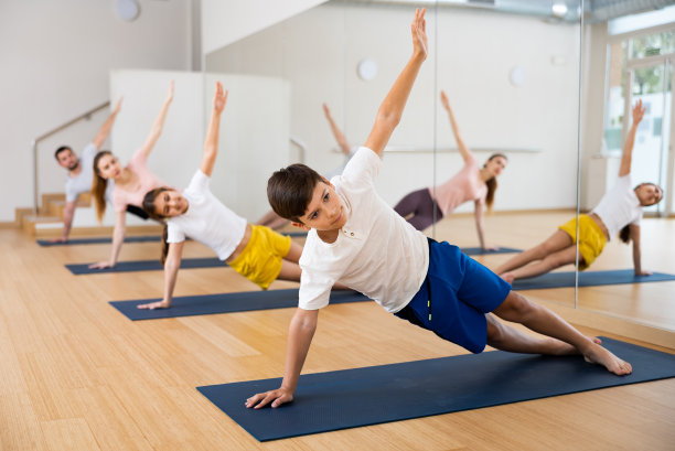 男孩和她的家人在垫子上练习侧平板支撑图片下载