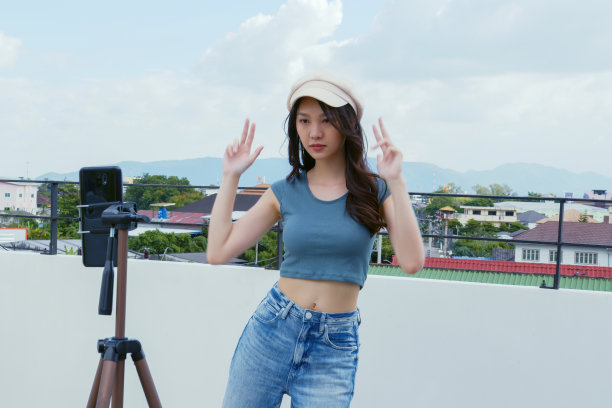 日落时分，一名年轻的亚洲女子在室外屋顶上用智能手机摄像头拍摄了她的舞蹈视频。在社交媒体应用上分享视频图片下载