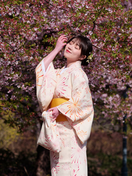 美丽的年轻中国女孩在日本和服摆闭眼与樱花背景在春天的花园，美丽，情感，生活方式，表达和人的概念。图片下载