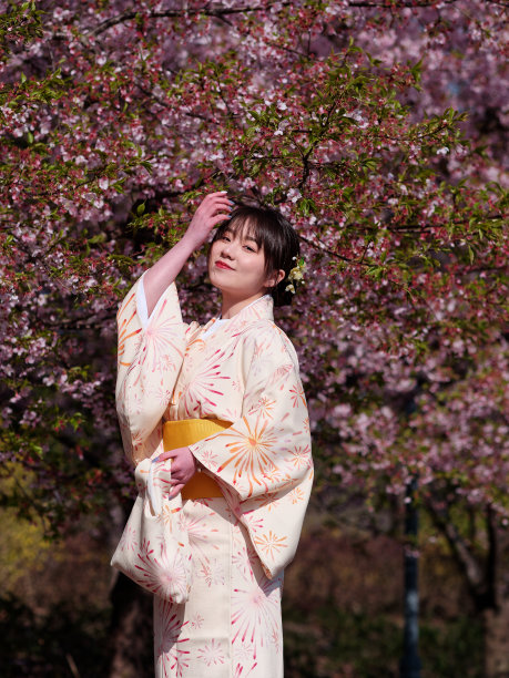 美丽的年轻中国女孩在日本和服摆姿势与樱花背景在春天的花园，美丽，情感，生活方式，表达和人的概念。图片下载