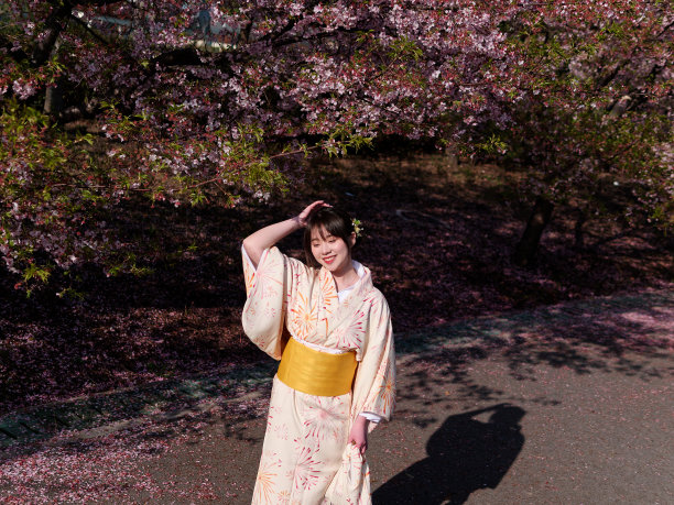 美丽的年轻中国女孩在日本和服摆闭眼与樱花背景在春天的花园，美丽，情感，生活方式，表达和人的概念。图片下载