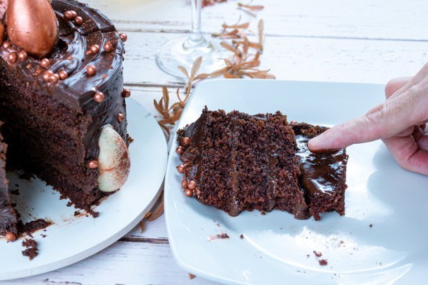 男性手指触摸黑巧克力蛋糕甘纳许馅。图片下载