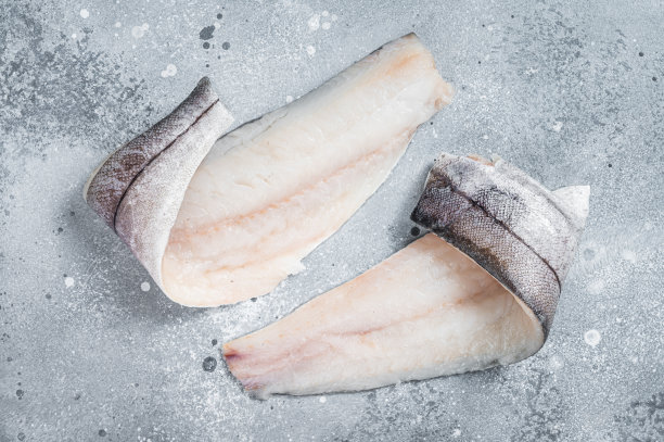 餐桌上有两条生黑线鳕鱼片。灰色的背景。俯视图图片下载