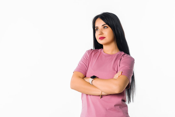严肃迷人的黑发女孩站在双臂交叉。迷人的年轻女子在封闭的姿势对白色工作室背景摆姿势图片下载