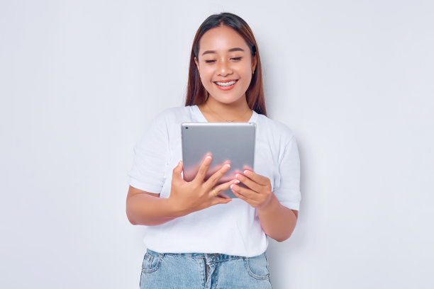 穿着白色t恤的年轻亚洲女孩微笑着在白色背景的数字平板电脑上看到一个在线报价图片下载