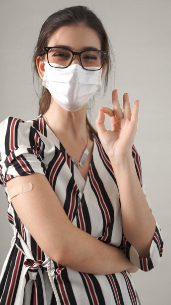 年轻女子在新冠病毒疫苗接种计划的概念中愉快地展示COVID-19疫苗绷带，为公民接种疫苗。图片下载