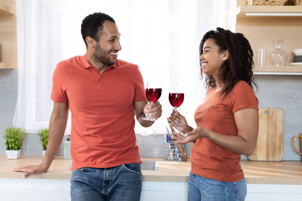 快乐的千禧一代黑人女士和戴眼镜的男人举起红酒杯，碰杯庆祝，聊天享受空闲时光图片下载