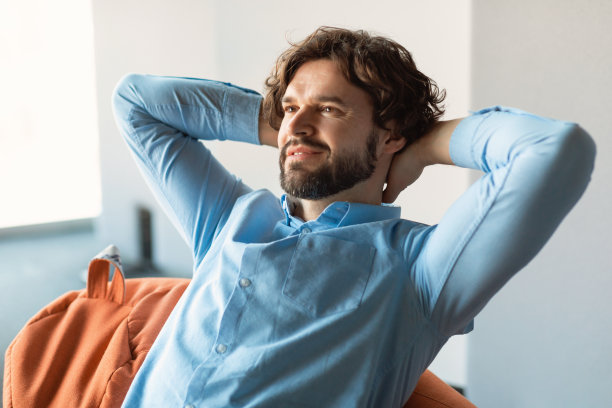 微笑的中年男子坐在豆袋上思考图片下载