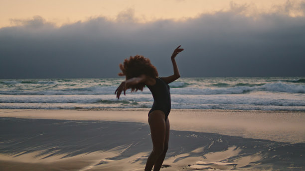 剪影灵活的舞者弯曲性感的身体在灰色多云的天空。女孩表演图片下载