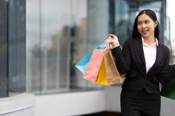 年轻美丽的亚洲女人拿着五颜六色的购物袋走在城市里。快乐的女人购物袋享受购物。消费主义，生活方式城市理念。图片下载