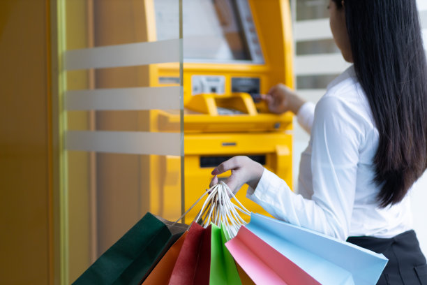 一名女子在自动取款机前用现金卡购物。图片下载