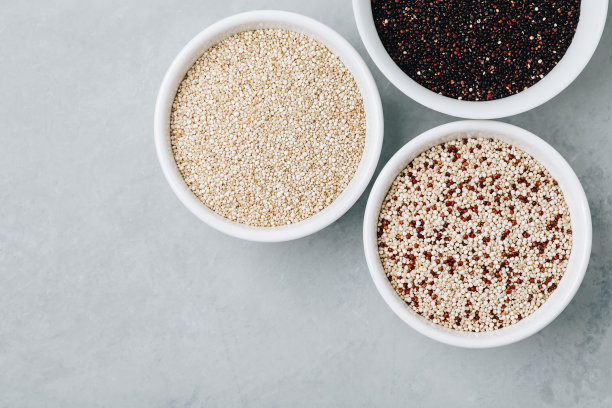 奎奴亚藜喜忧参半。红色黑白藜麦种子在碗上的灰色石头背景，俯视图。图片下载