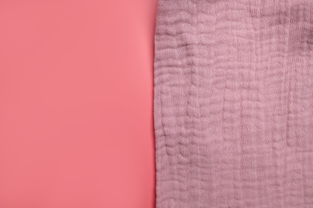 粉红色的细棉布织物的纹理在粉红色的背景。棉纺织和服装。柔软细腻的天然有机棉面料，适用于缝纫、针线活、婴儿毛巾、尿布、连衣裙。织物背景图片下载