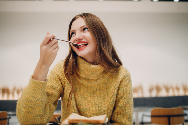 年轻女子在室内咖啡馆吃三明治图片下载